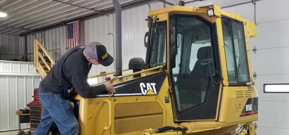 Mechanic performing equipment repair on a Caterpillar D5G bulldozer at Black Hills Equipment Rentals in Spearfish, SD.