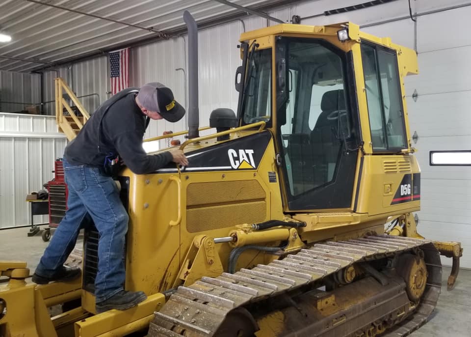 Mechanic performing equipment repair on a Caterpillar D5G bulldozer at Black Hills Equipment Rentals in Spearfish, SD.