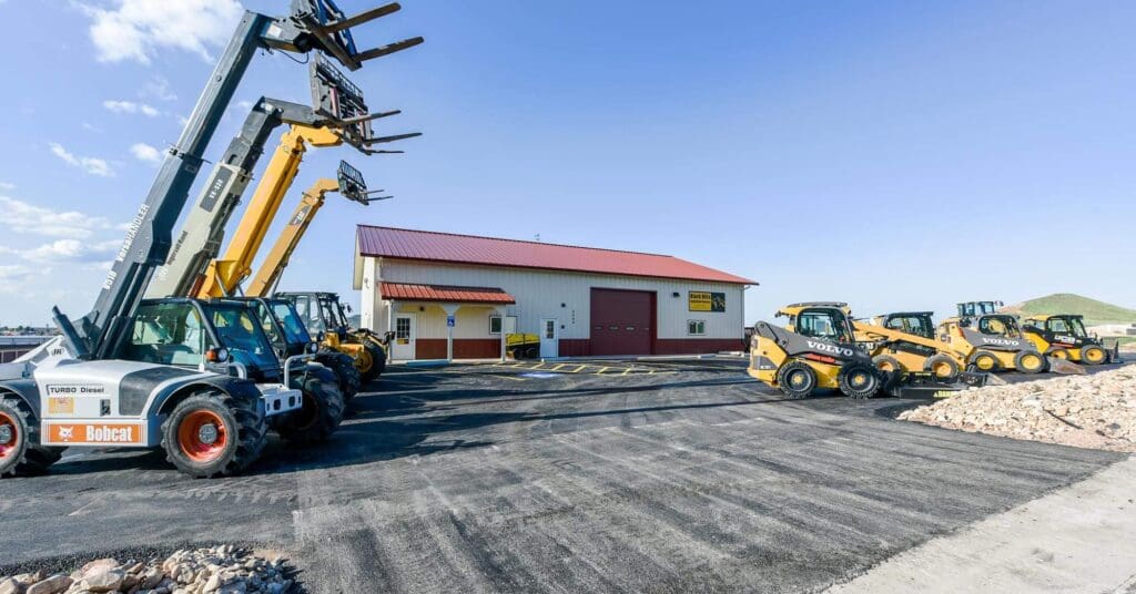 Black Hills Equipment Rentals facility in Spearfish, SD with telehandlers, skid steers, and heavy construction equipment lined up outside for rental and sales.
