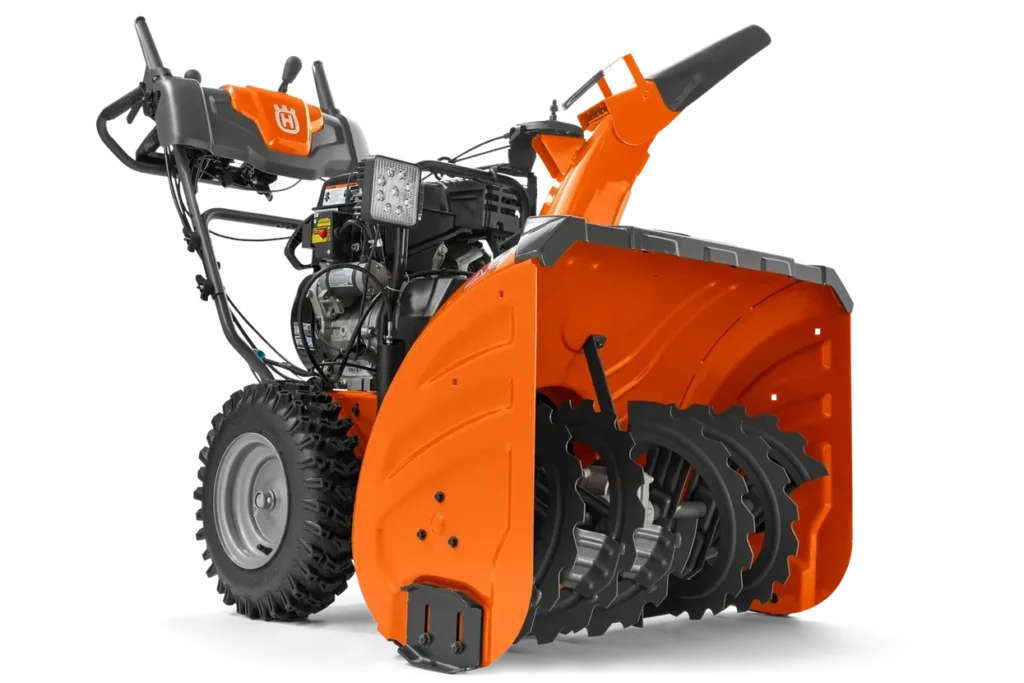 Husqvarna two-stage snowblower with large auger, LED headlight, and orange housing on a white background.